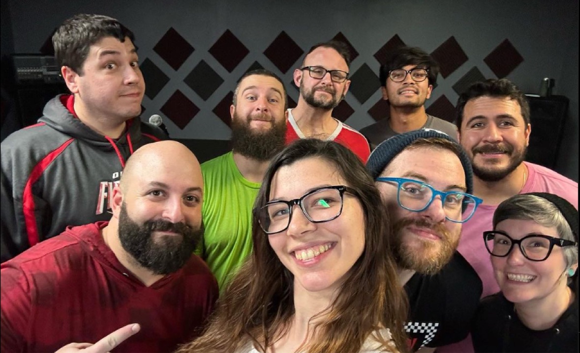 All nine members of Backyard Superheroes together in the rehearsal room, gathered for a group selfie