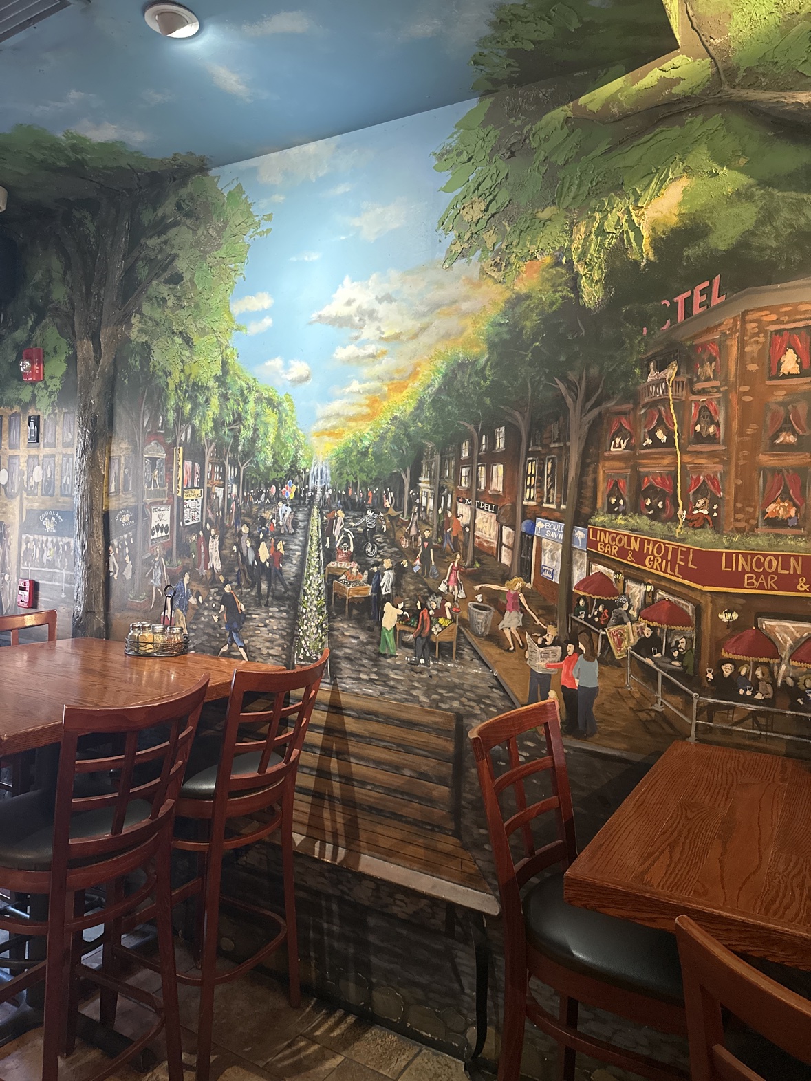 The big street-scene mural inside Ferraro's — a painted tree-lined boulevard of shops and crowds, with the Lincoln Hotel Bar & Grill on the corner
