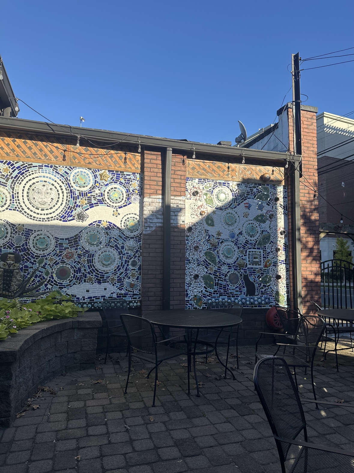 The Ferraro's patio at dusk-blue daylight, its walls covered in mosaics of moons, stars and faces