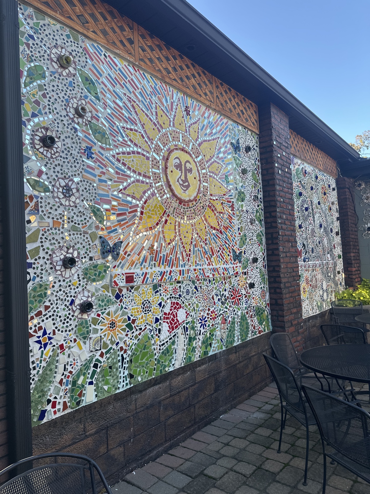 The patio wall at Ferraro's, covered in a colorful mosaic of a smiling sun surrounded by flowers and butterflies