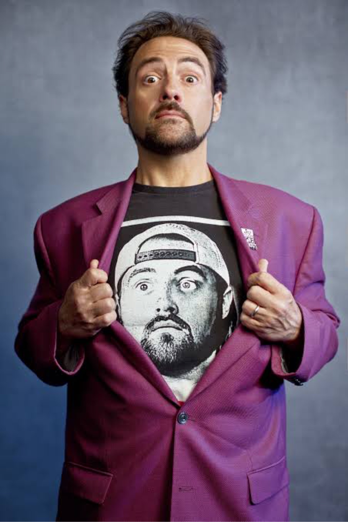 Kevin Smith in a purple blazer, pulling it open to reveal a t-shirt with his own Silent Bob face